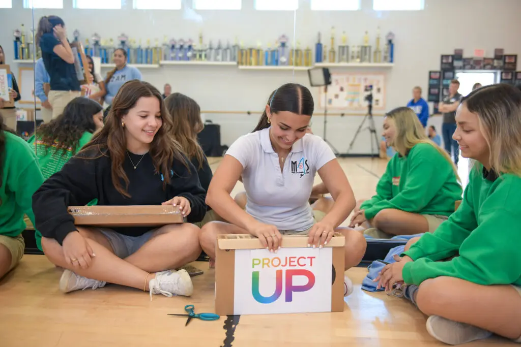 Girls sitting on the floor open a box