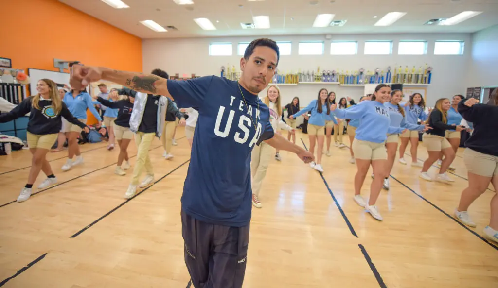 man doing a dance demonstration to a group of students