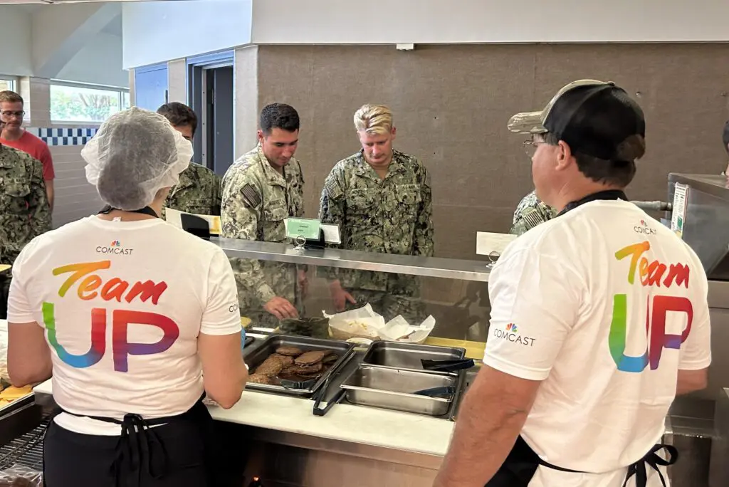 two people serving lunch to members of the navy