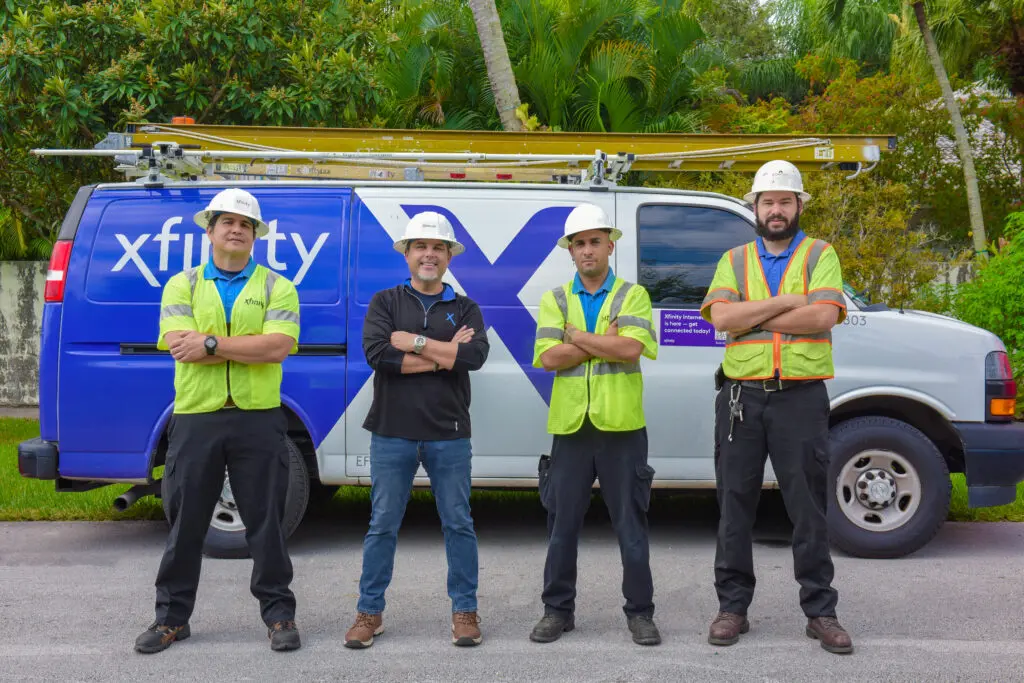 Four men pose for a photo in front of a van