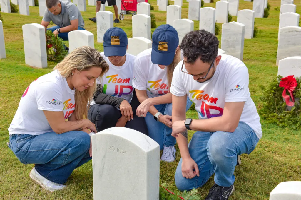 group of people pay tribute to fallen veteran at his grave
