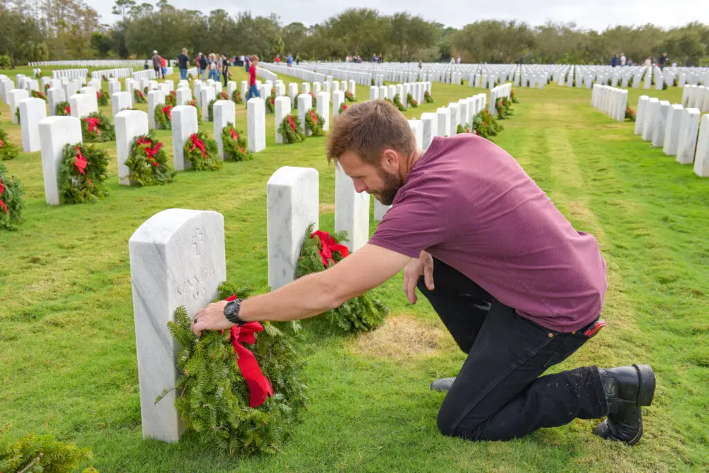 man lays wreath at relative's grave