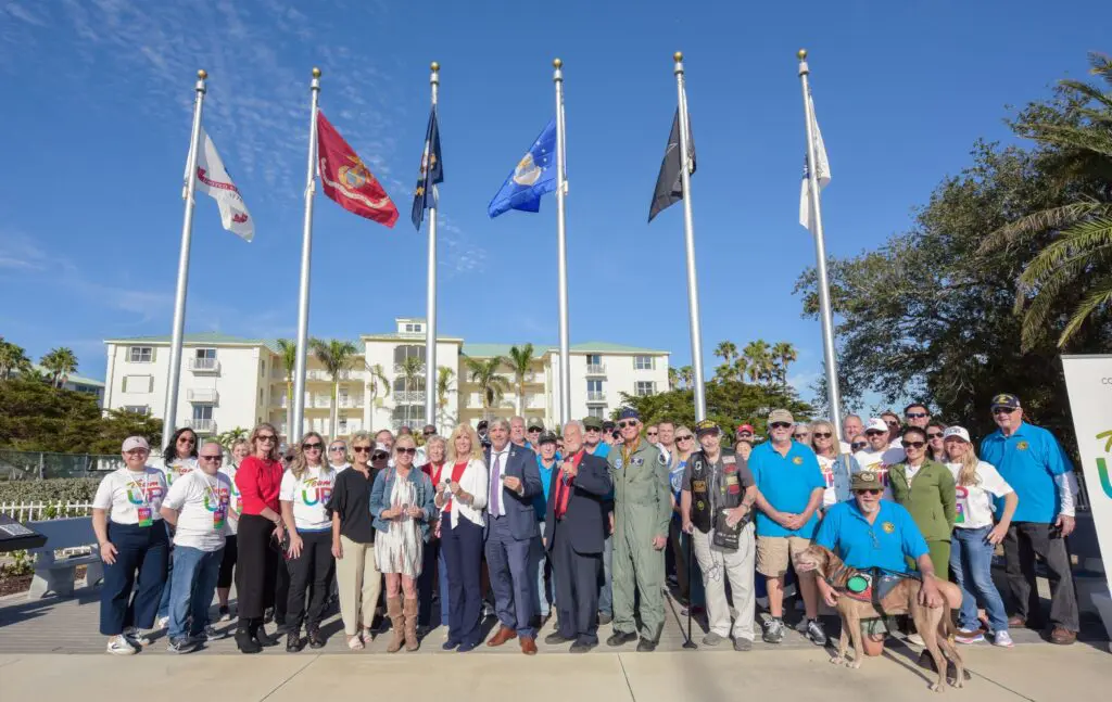 people posing for a picture in front of flags at a park