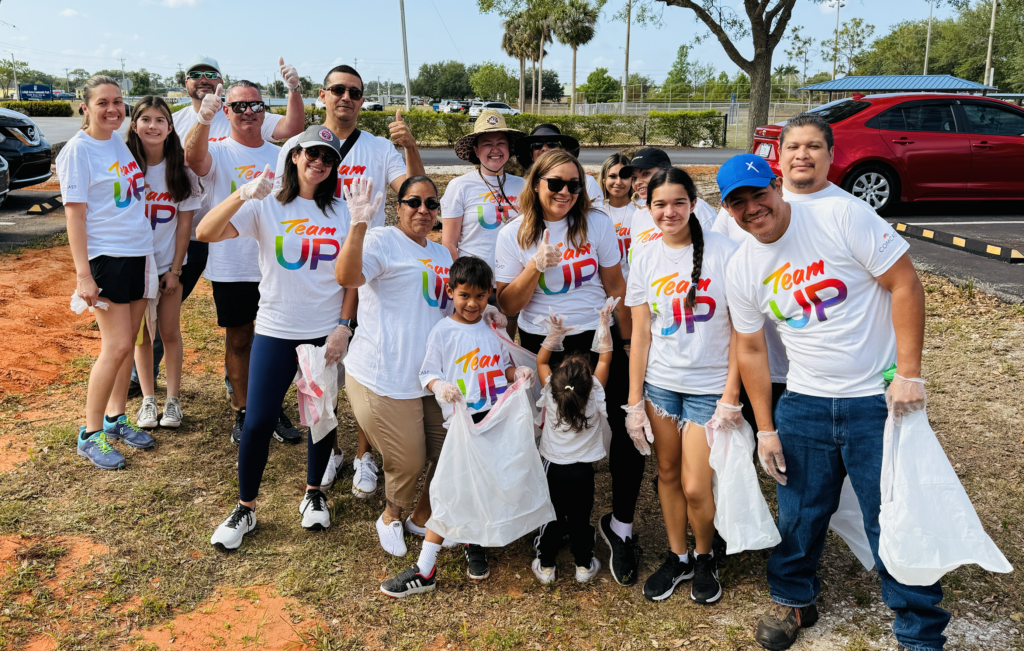 people posing for a picture at a park with garbage bags in their hands.