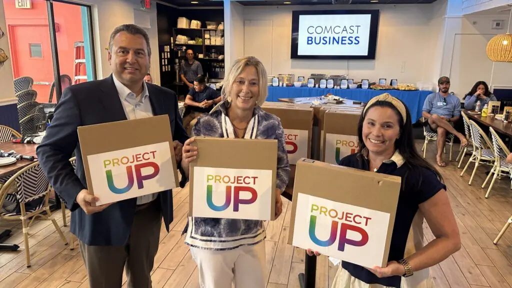 Jeff Buzzelli of Comcast, Angela Hemstreet of Goodwill Industries SWFL and Shari Cortese of Comcast Business pose with the donated laptops.