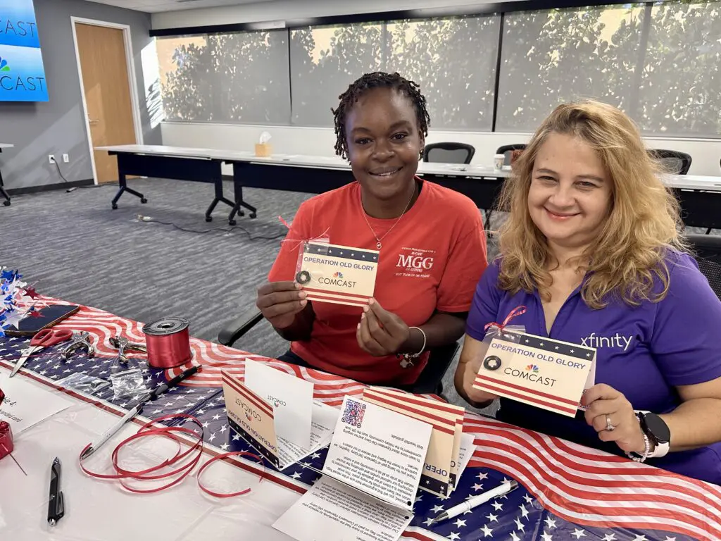 two women smile and pose with cards in their hands