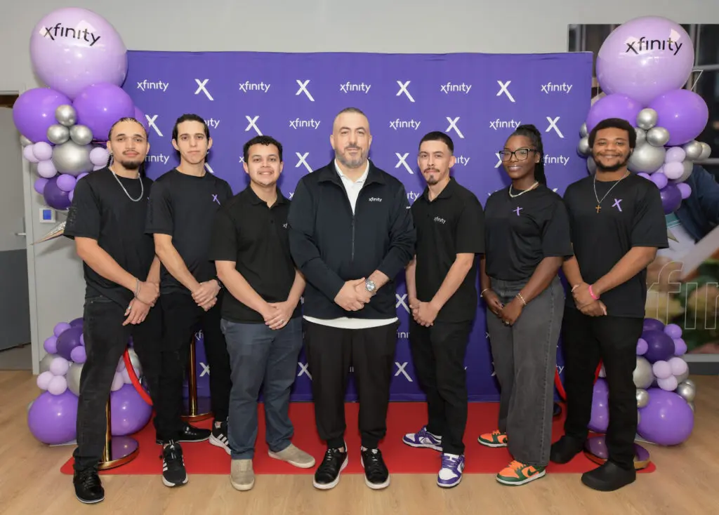 Seven people posing in front of an Xfinity step-and-repeat. 
