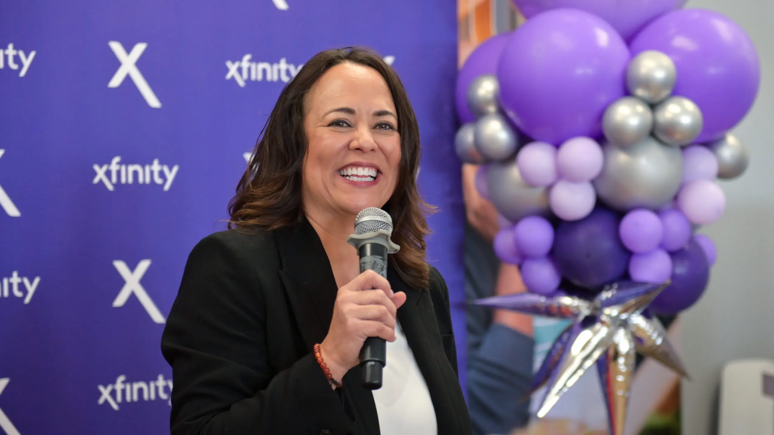 Woman holding a microphone and giving remarks. 