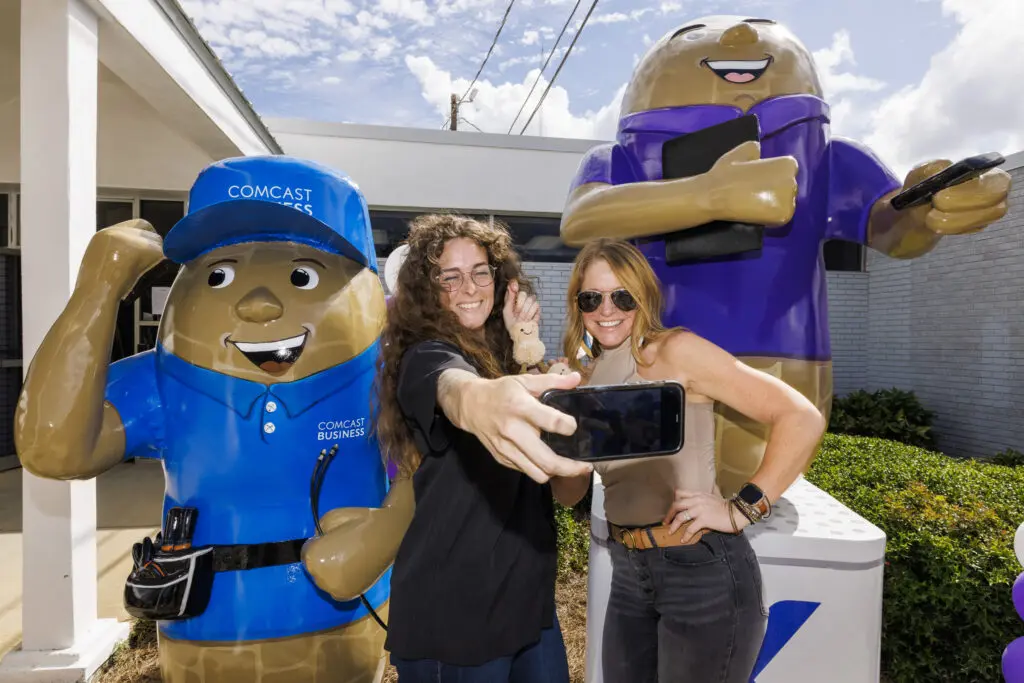 Attendees take photos with the newly unveiled Xfinity and Comcast Business-inspired peanut sculptures.