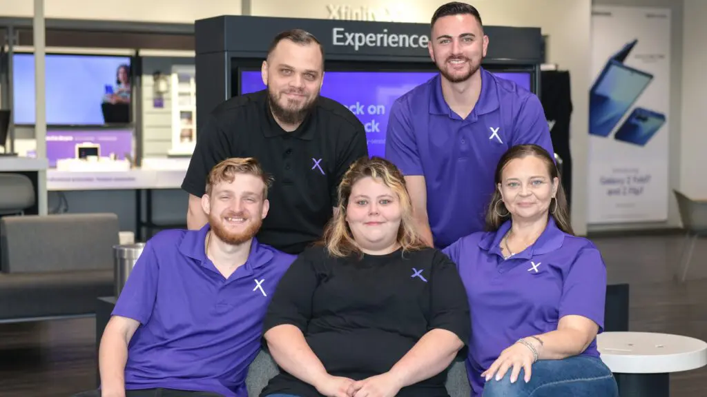 Brent Delawter standing with his team inside the Lady Lake Xfinity Store, all smiling and wearing Comcast-branded attire.