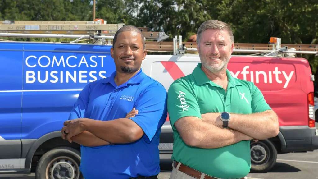 Comcast technicians wearing uniforms and posing with their vans in The Villages.