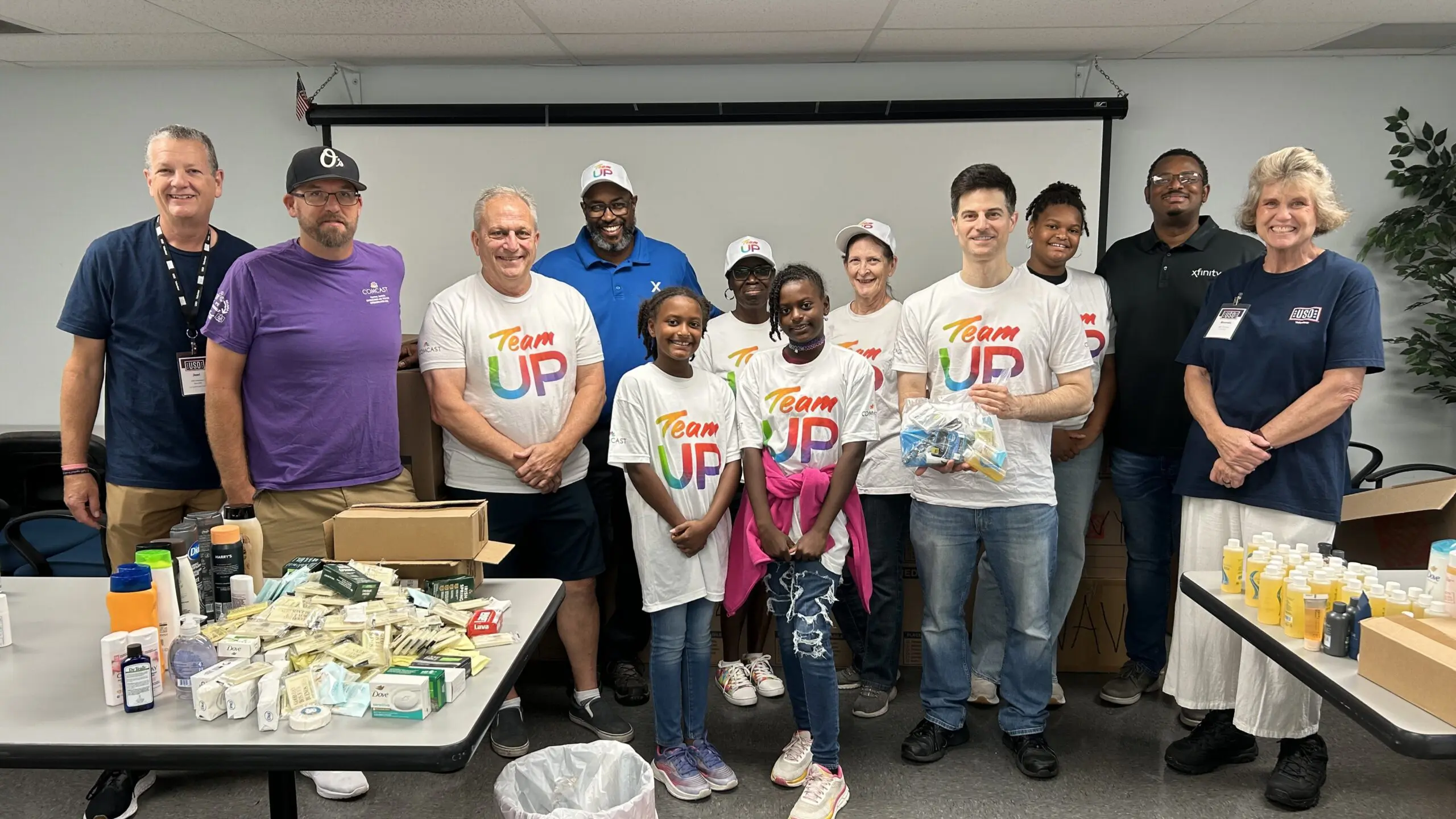 A group of Comcast volunteers smiling together at the USO Jacksonville center after assembling hygiene kits for service members.