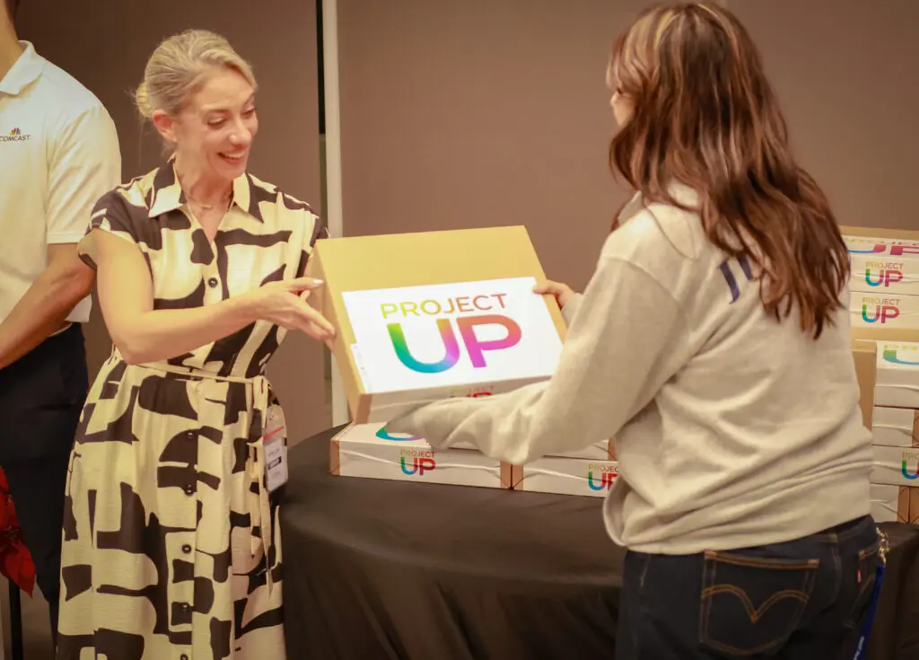 A 7th grader holds up his new laptop in Miami's Overtown neighborhood with the help of Comcast's Project UP donation to advance digital literacy. 