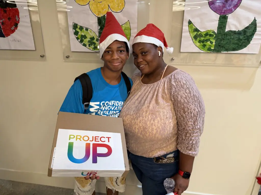A 7th grader holds up his new laptop in Miami's Overtown neighborhood with the help of Comcast's Project UP donation to advance digital literacy. 