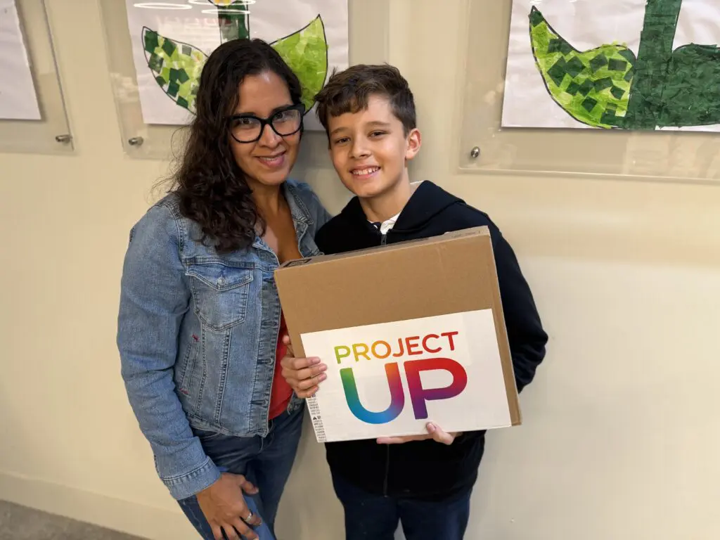 A 7th grader holds up his new laptop in Miami's Overtown neighborhood with the help of Comcast's Project UP donation to advance digital literacy. 