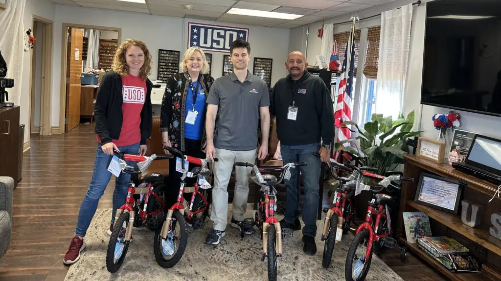 Comcast and USO leaders smile with the donated bikes.