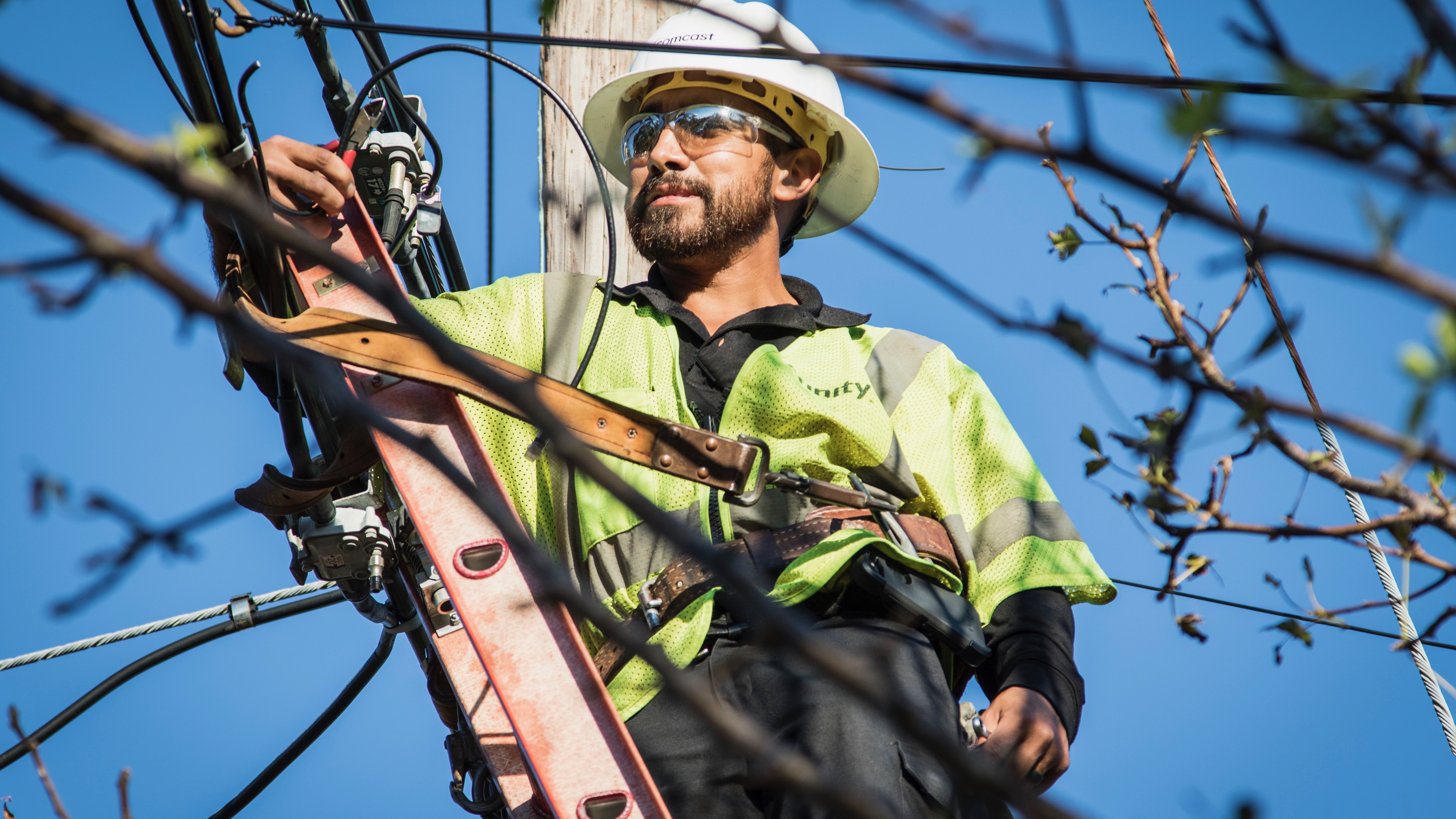 An Xfinity lineman working on a telephone pole.