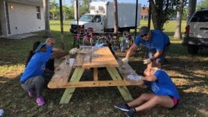 Comcast Cares Day volunteers refinish a picinic table.