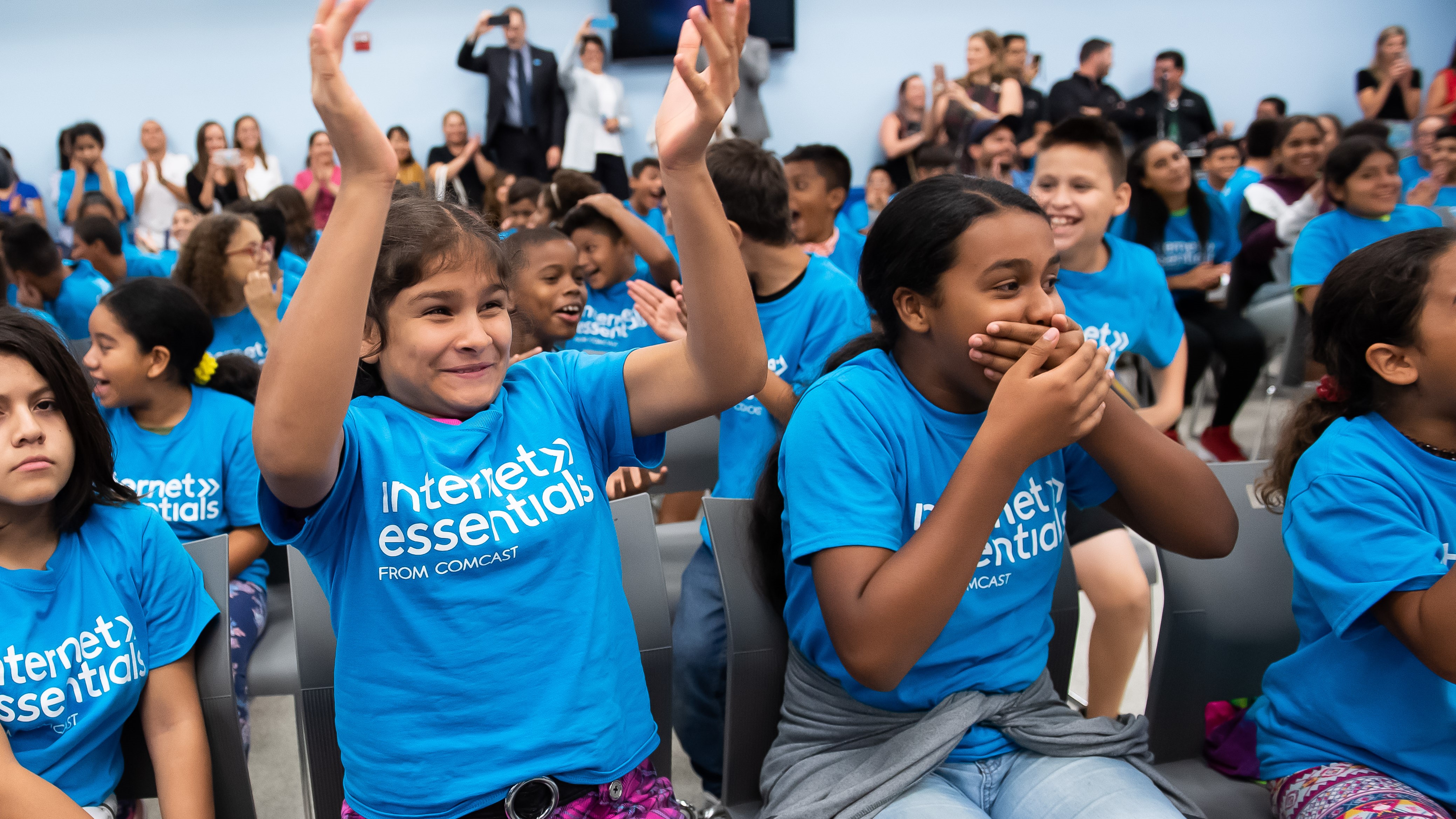 A group of children cheer at an Internet Essentials event.