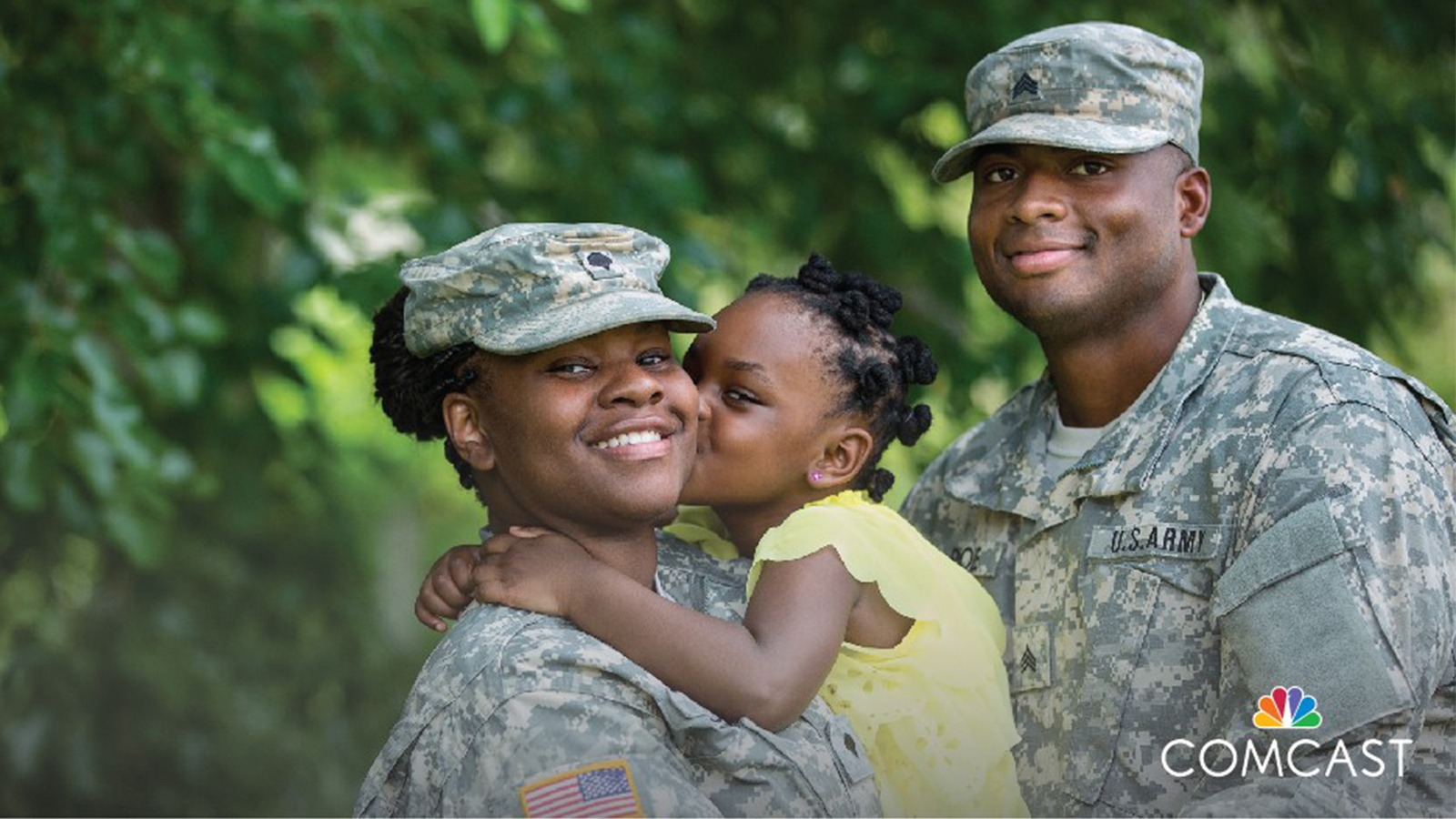 A male and female dressed in a military uniform holding a young child.