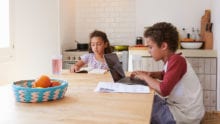 Two students do their homework at a kitchen table
