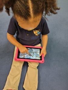 Young girl playing fame on a tablet.