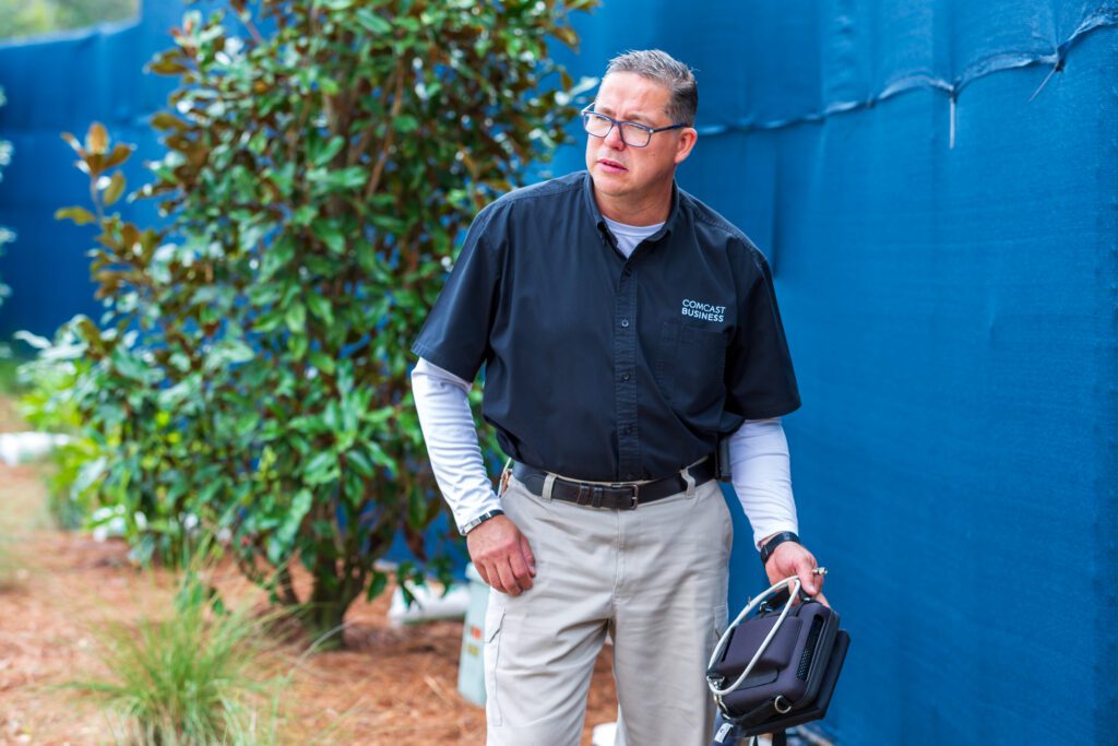 A man holding equipment with a Comcast Business shirt on