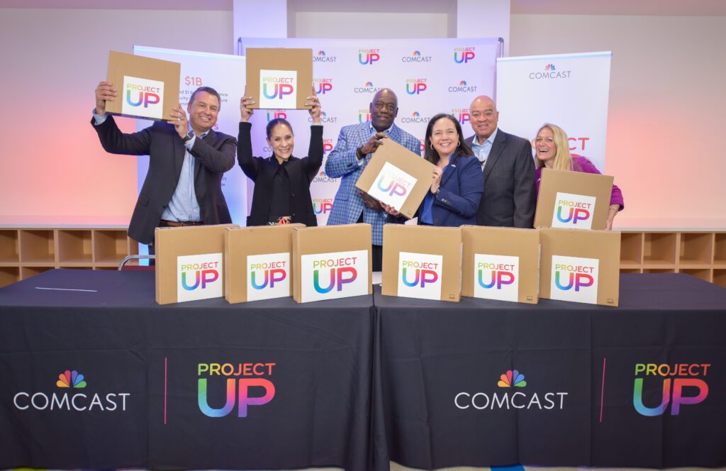 A group of people posing with new laptops.