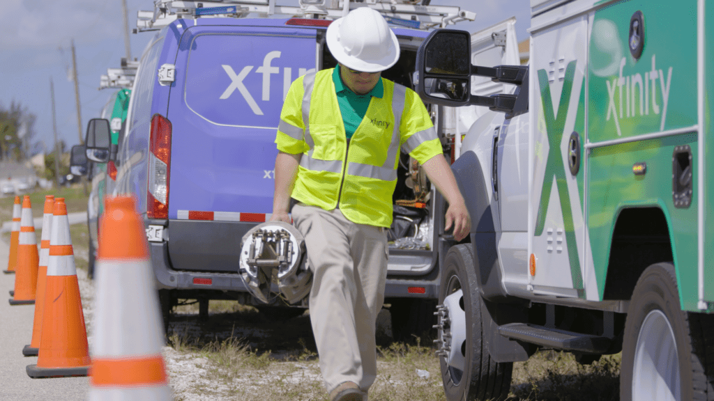 A Comcast tech walks alongside Xfinity trucks.