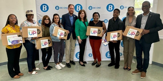 Men and women pose for a picture with laptops in hand.