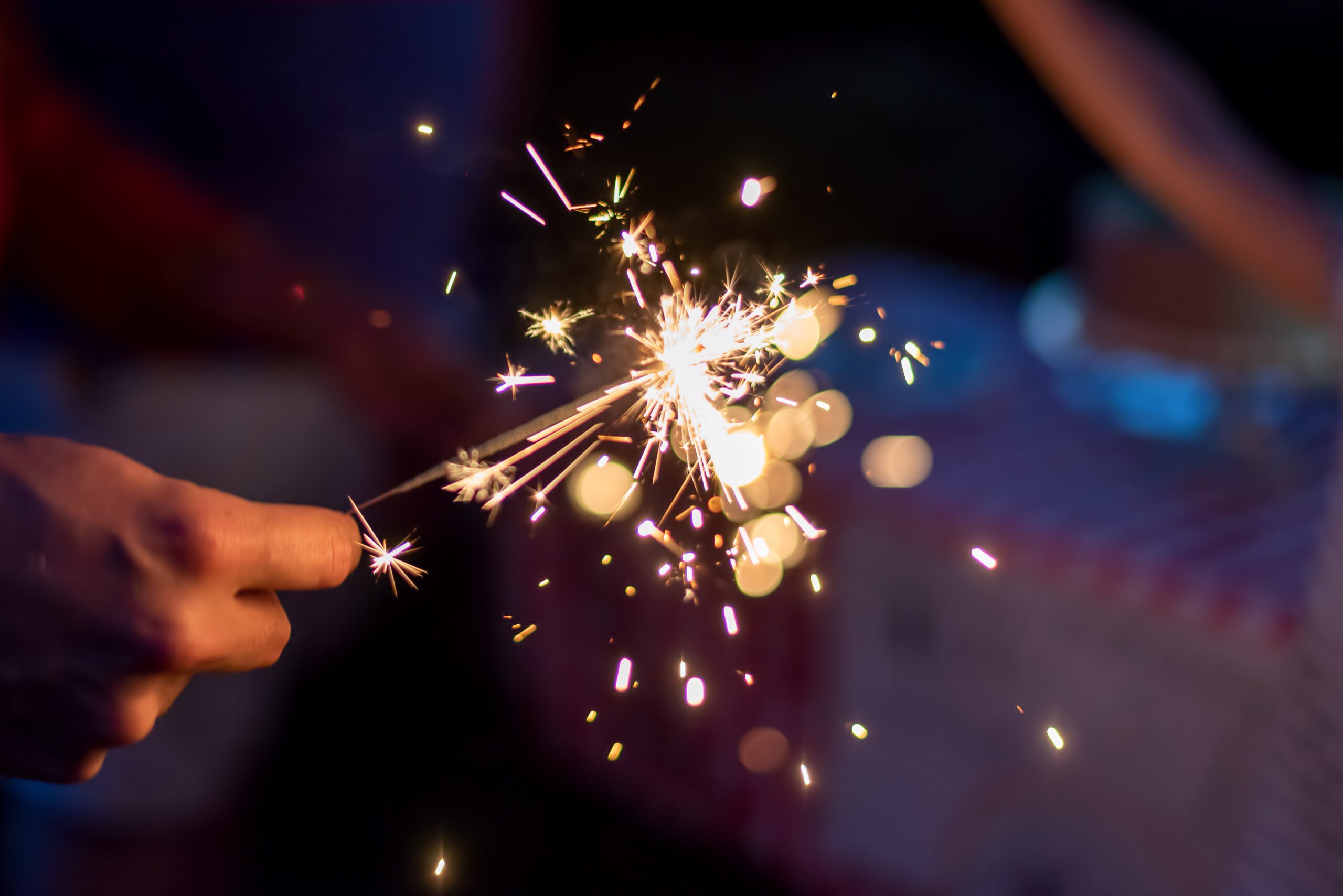 Hand holding a sparkler during blue hour in the backyard at a family celebration