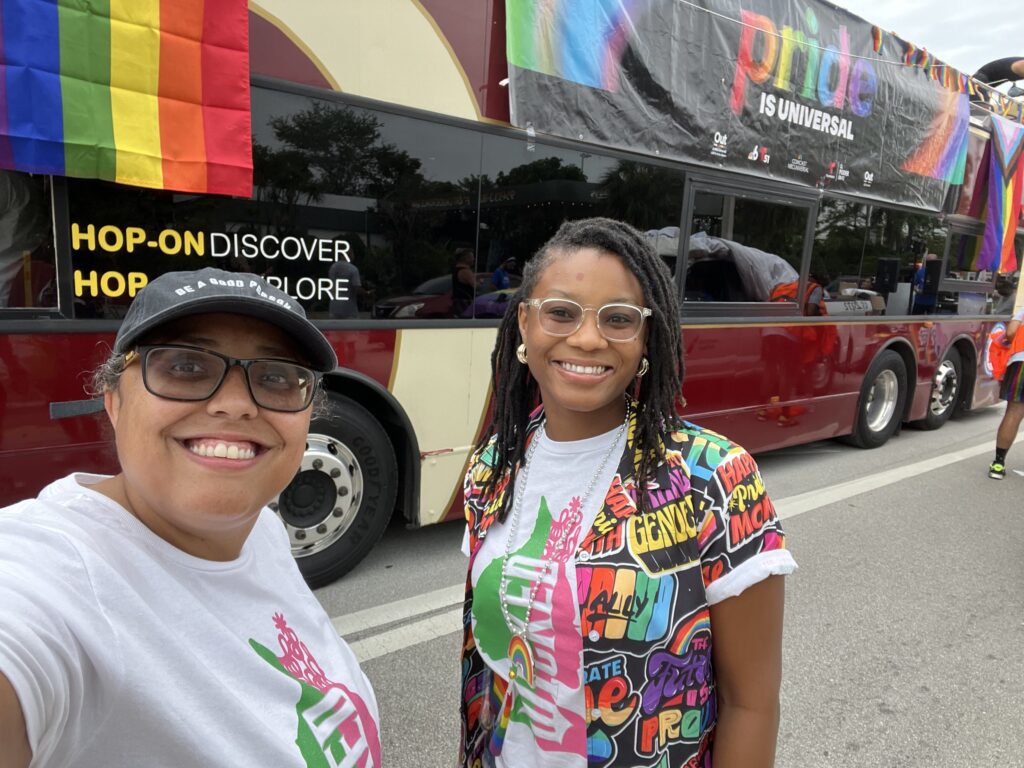 two women pose for a picture next to a bus