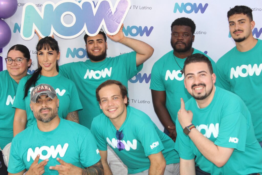 eight people pose for a picture with a now sign 