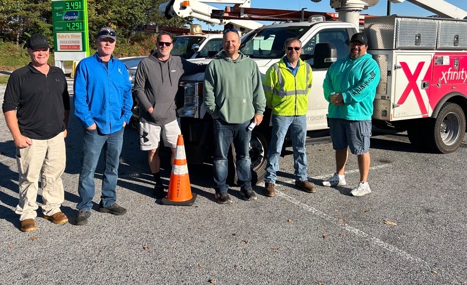 Comcast crews traveling to Florida stand in front of an Xfinity truck