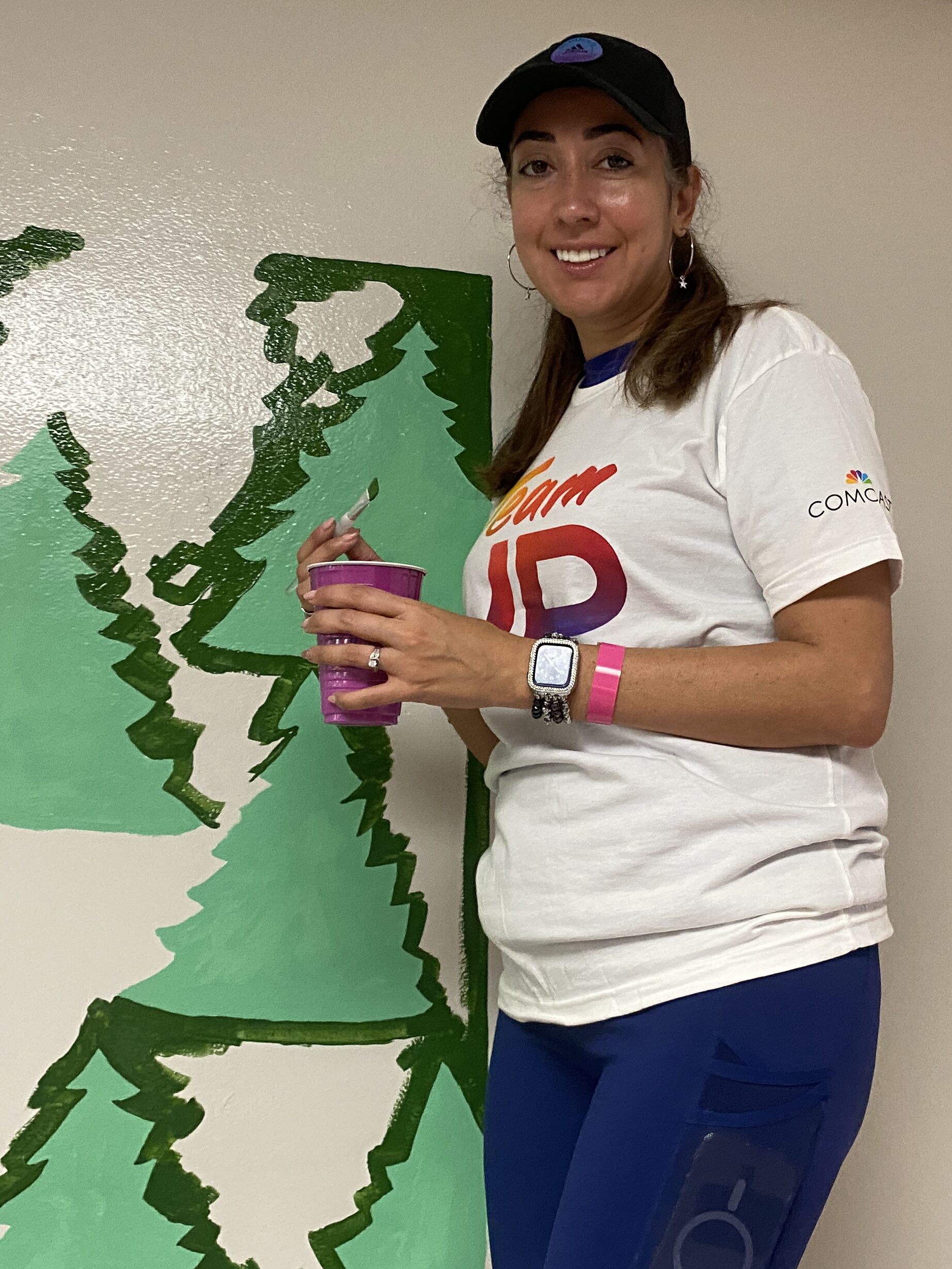 A Comcast volunteer paints a mural in the hallway of the elementary school.