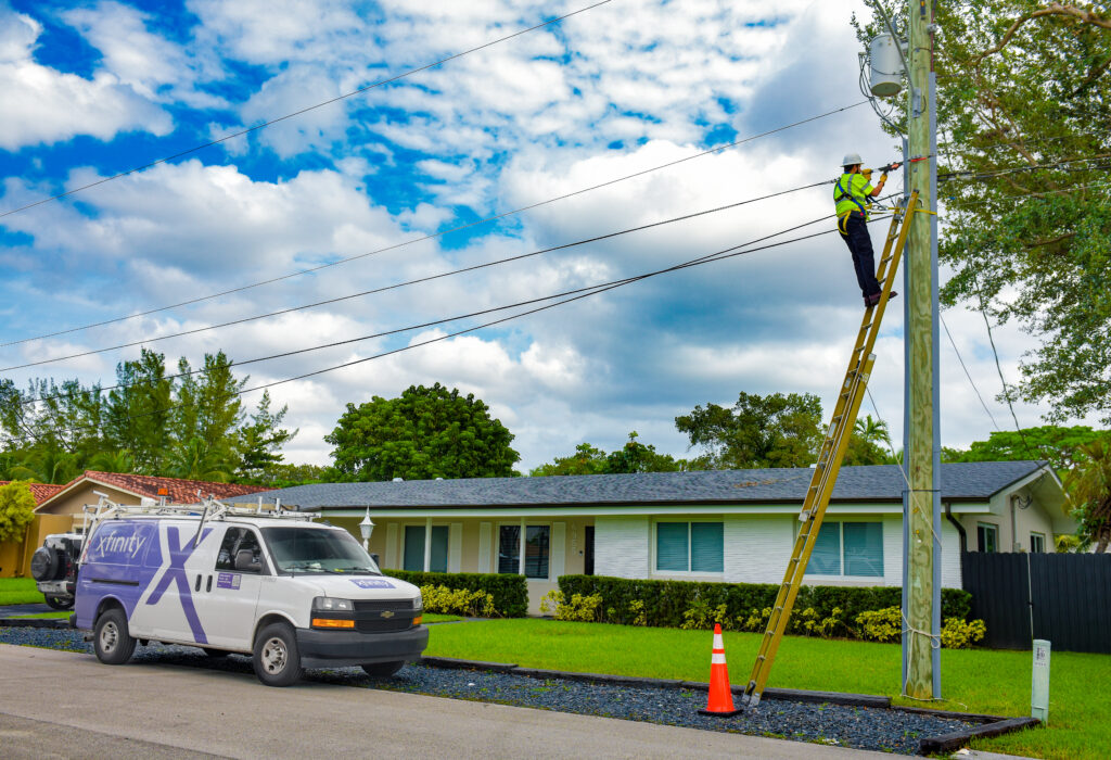 An Xfinity technician works on a ladder.