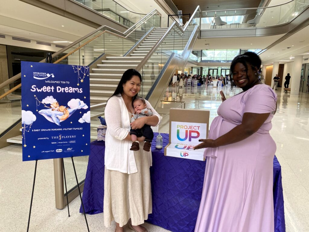 New mom Kaye Peterson with her son Hudson, two months, and expecting mom Victoria Wuttke smile while receiving their laptops.