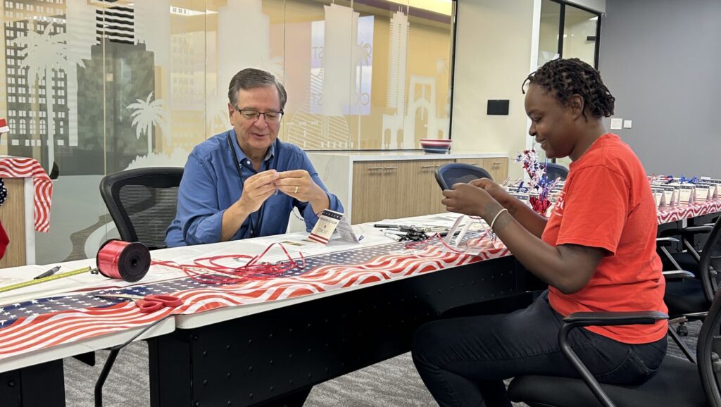 Man and woman create keepsakes with grommets obtained from retired American flags.