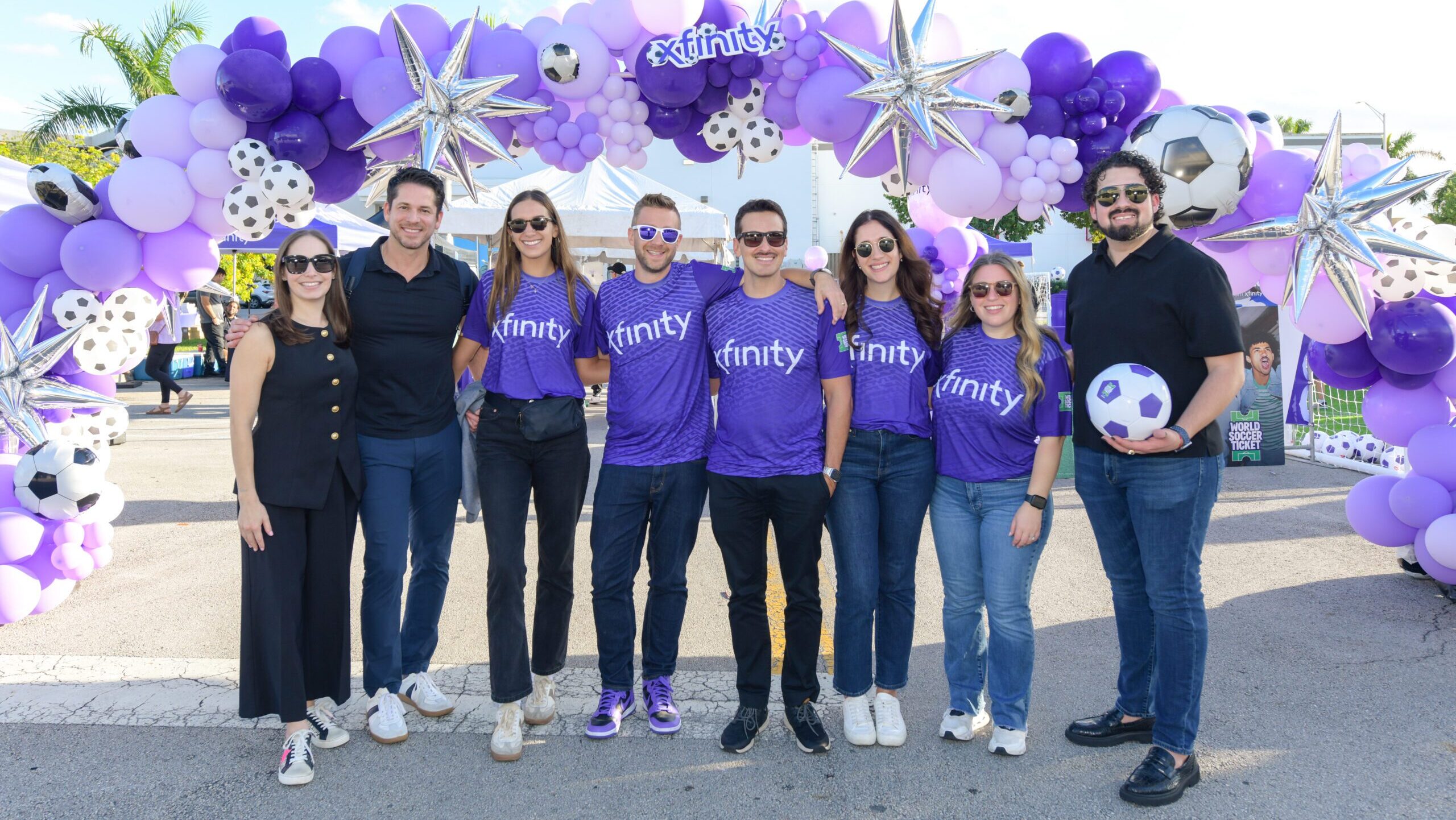 group of people posing under a balloon arch