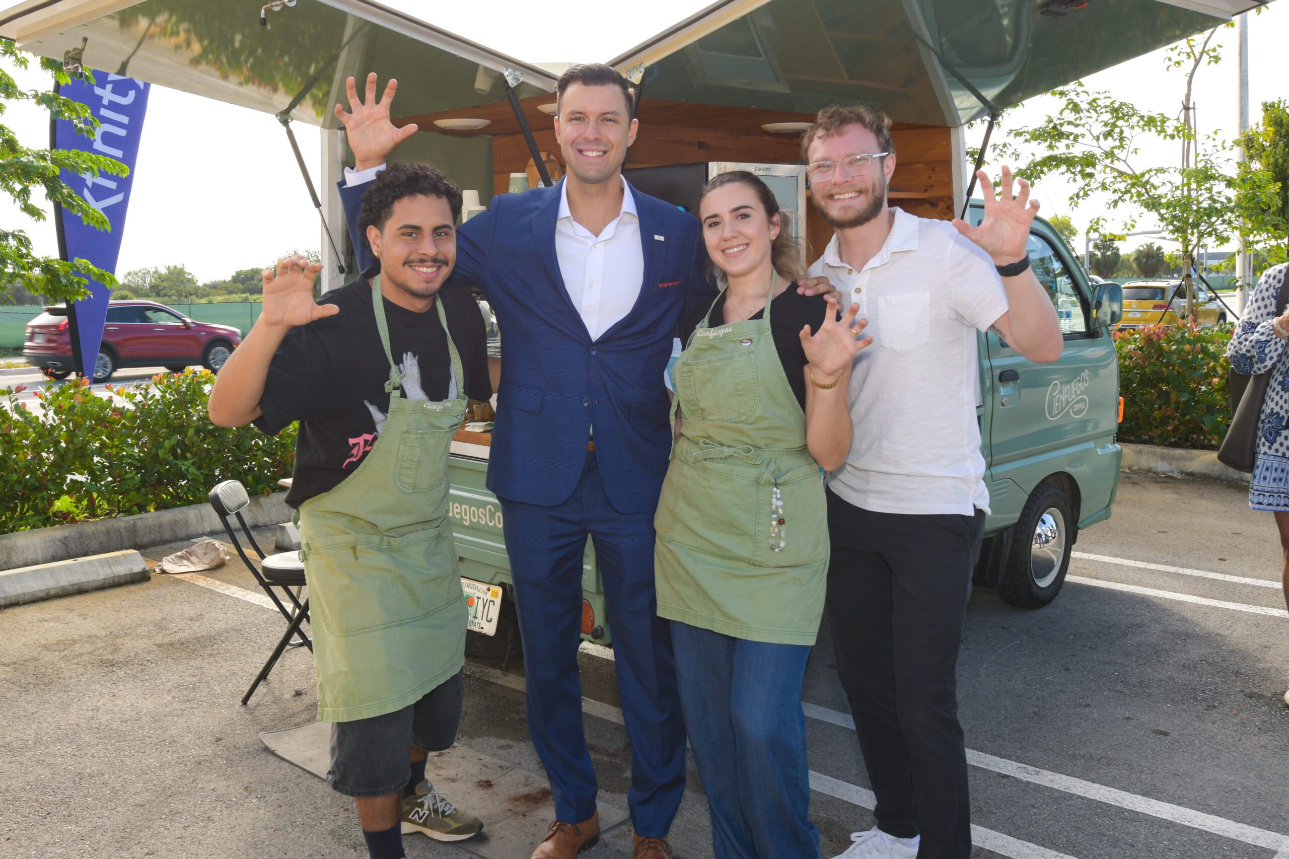 People posing for a picture by a coffee cart.