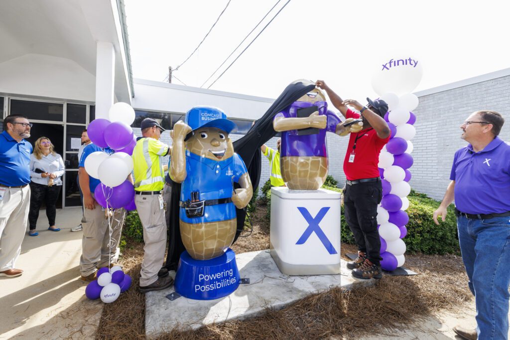 Comcast technicians help unveil two new peanut sculptures outside the Oates Street Xfinity Store in Dothan, AL.