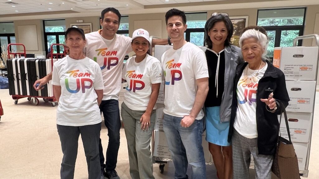 A group of Comcast volunteers smiling at Sacred Heart Catholic Church after participating in the Hunger Fight meal-packing event.