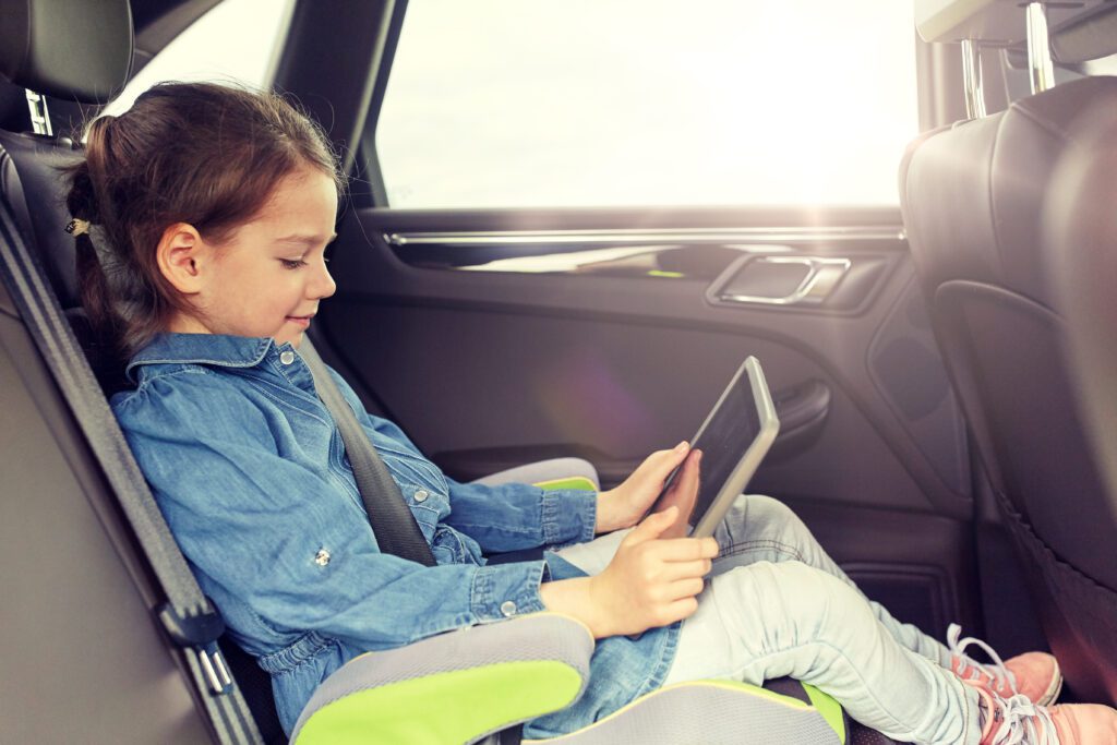 Child in car seat streaming holiday content on tablet while parents shop Black Friday and Cyber Monday deals online.