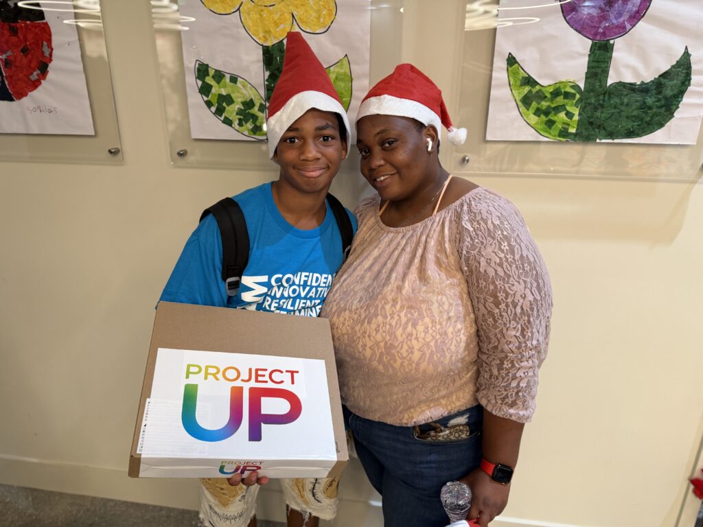 A 7th grader holds up his new laptop in Miami's Overtown neighborhood with the help of Comcast's Project UP donation to advance digital literacy. 