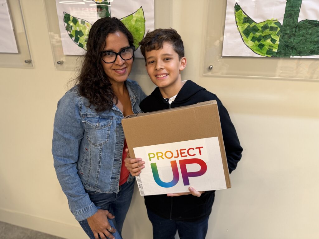 A 7th grader holds up his new laptop in Miami's Overtown neighborhood with the help of Comcast's Project UP donation to advance digital literacy. 