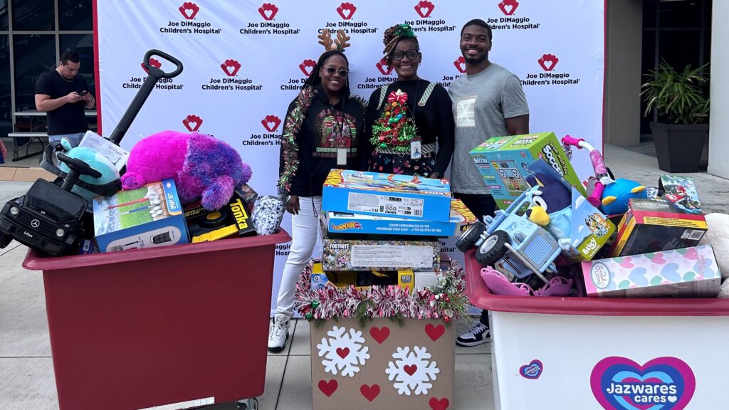 Volunteers pose with three large containers of toys.